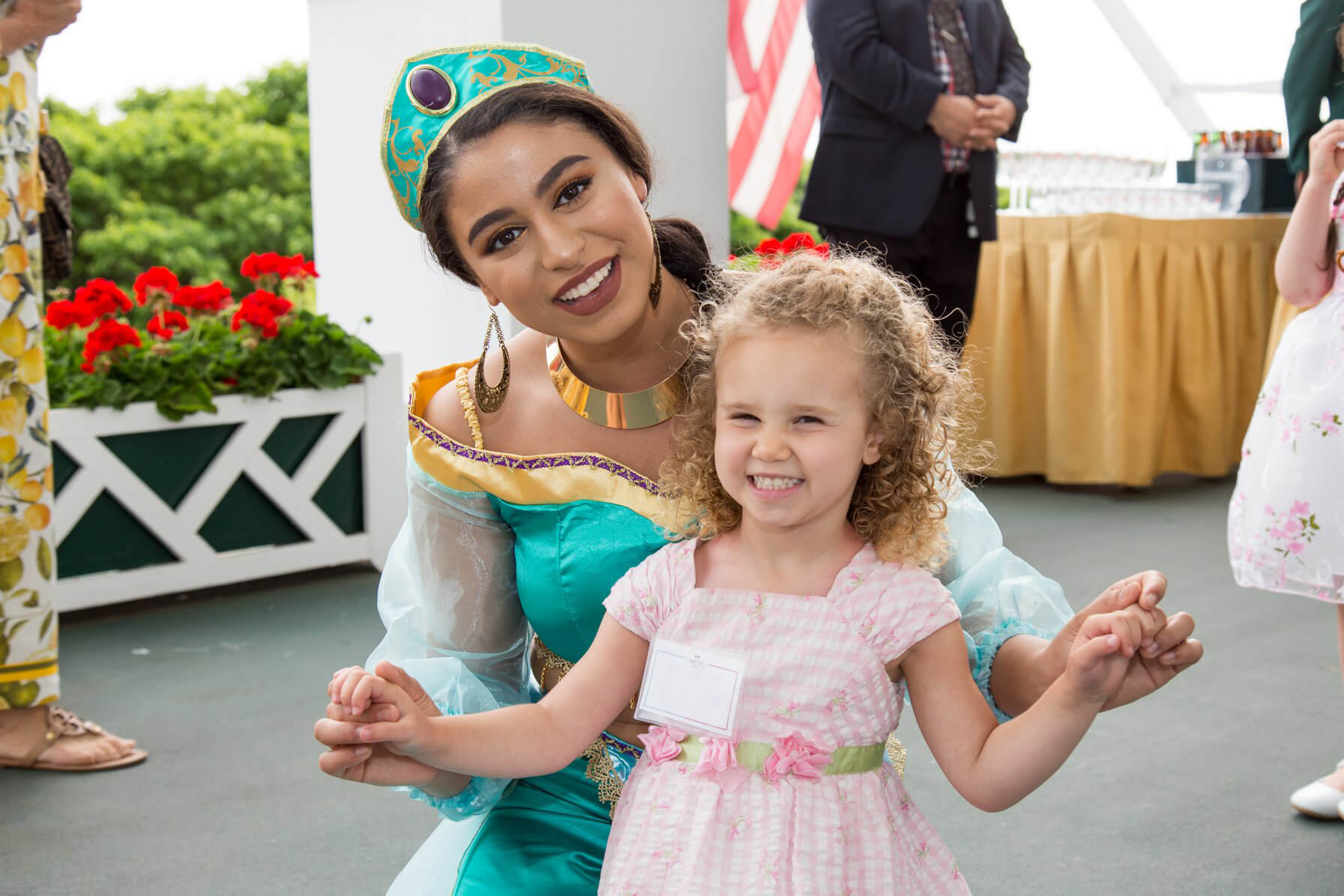 Princess Jasmine holds hands with a 3-year-old girl as they pose for a picture